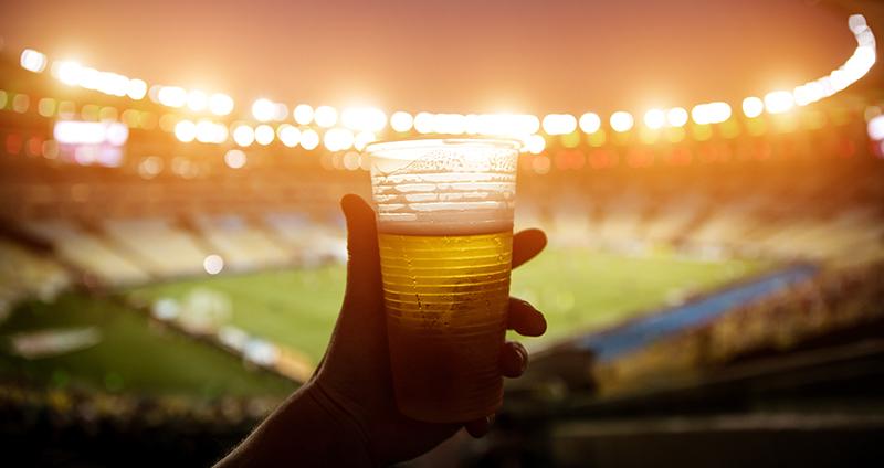 Fan holding beer at soccer stadium