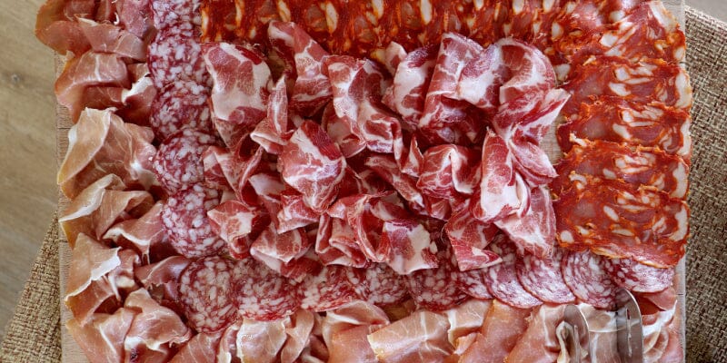 Soppressata in slices on a table next to other Italian Meats